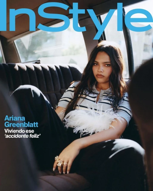 Ariana Greenblatt poses on the InStyle magazine cover, wearing a striped shirt with feathered trim and rings, seated in a car.