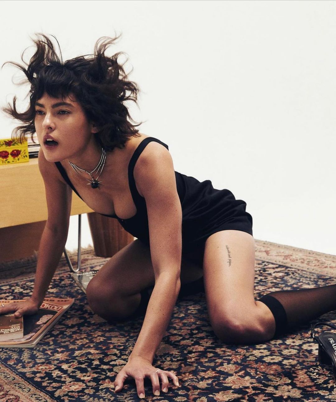 Woman in a black tank top and shorts on all fours on a patterned rug in Los Angeles shot by Jonny Marlow