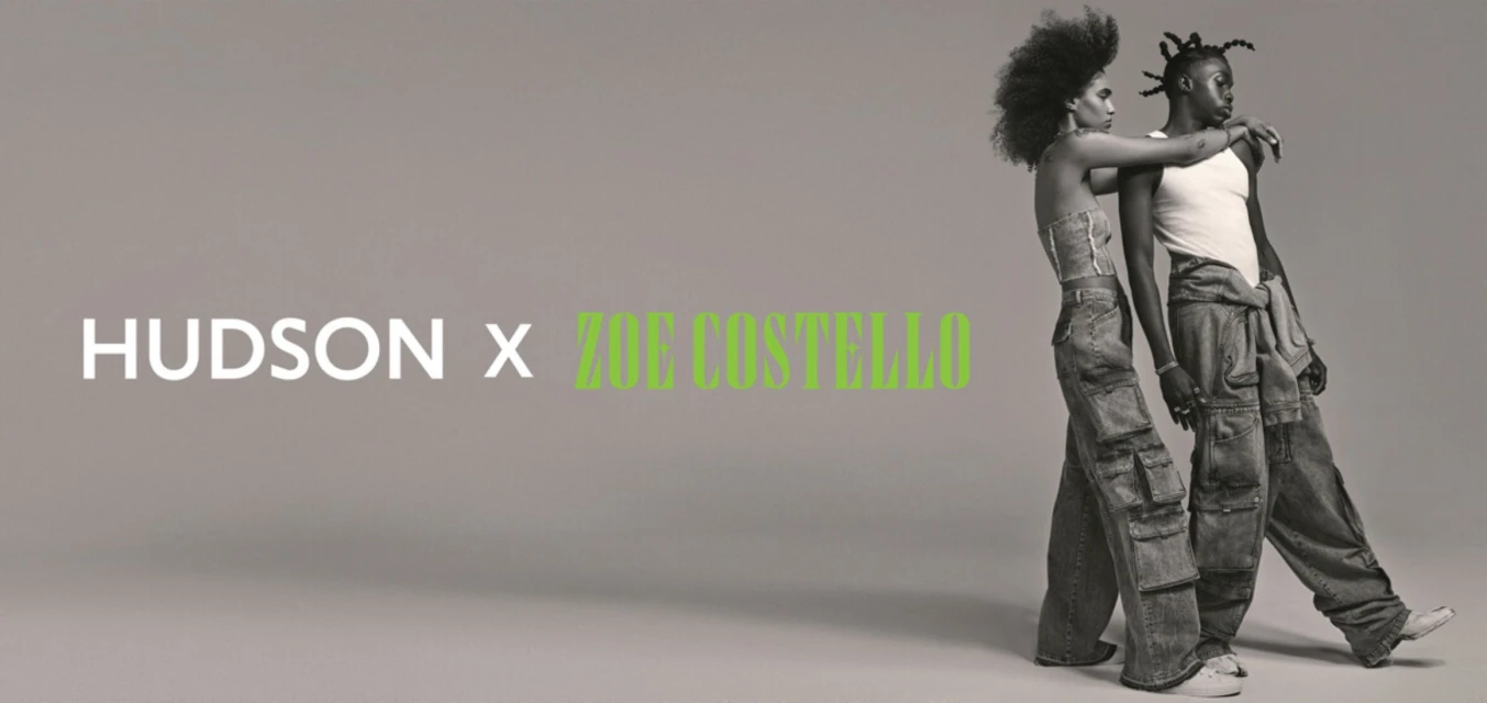 Fashion shot of a couple wearing matching denim cargo pants in front of a grey backdrop with the HUDSON x ZOE COSTELLO logo.