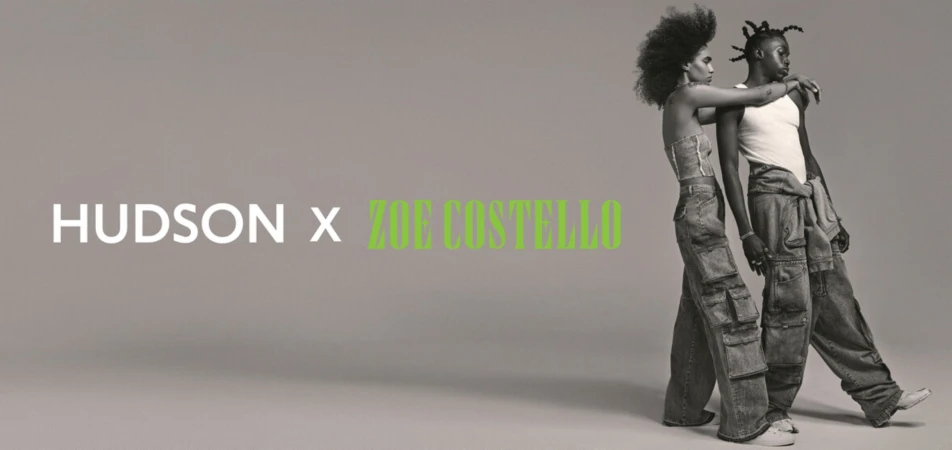 Fashion shot of a couple wearing matching denim cargo pants in front of a grey backdrop with the HUDSON x ZOE COSTELLO logo.