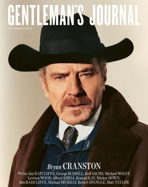 Bryan Cranston on Gentleman's Journal cover, wearing a brown coat and dark hat, against a neutral background in a medium portrait shot.