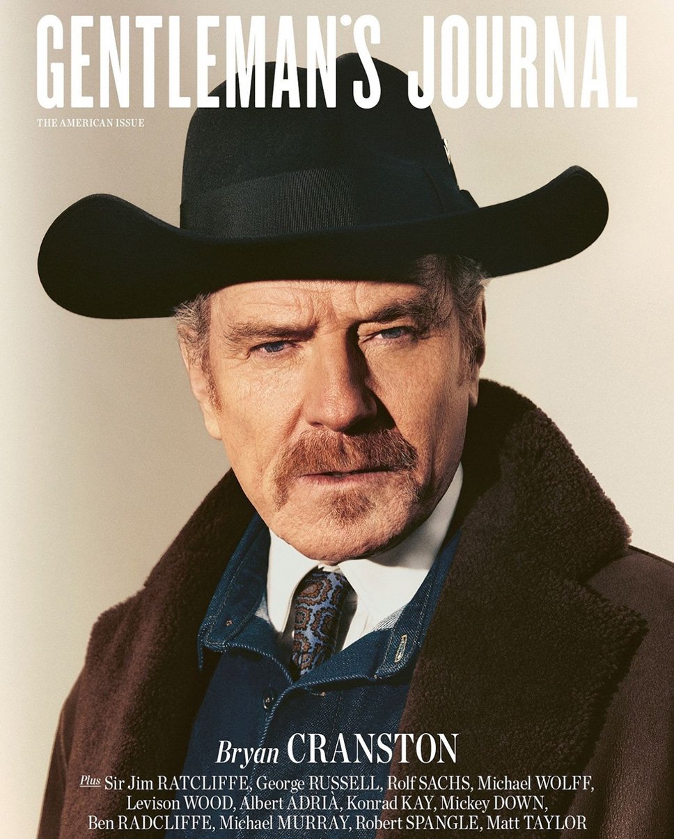 Magazine cover featuring Bryan Cranston in a black cowboy hat and brown coat, set against a neutral backdrop with magazine text overlay.