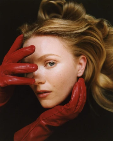 Close-up portrait of a woman wearing red leather gloves framing her face against a dark background