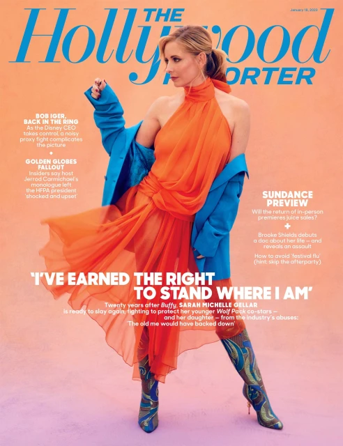 Magazine cover featuring Sarah Michelle Gellar wearing an orange dress, boots, and blue coat against a peach background, in a studio shot.