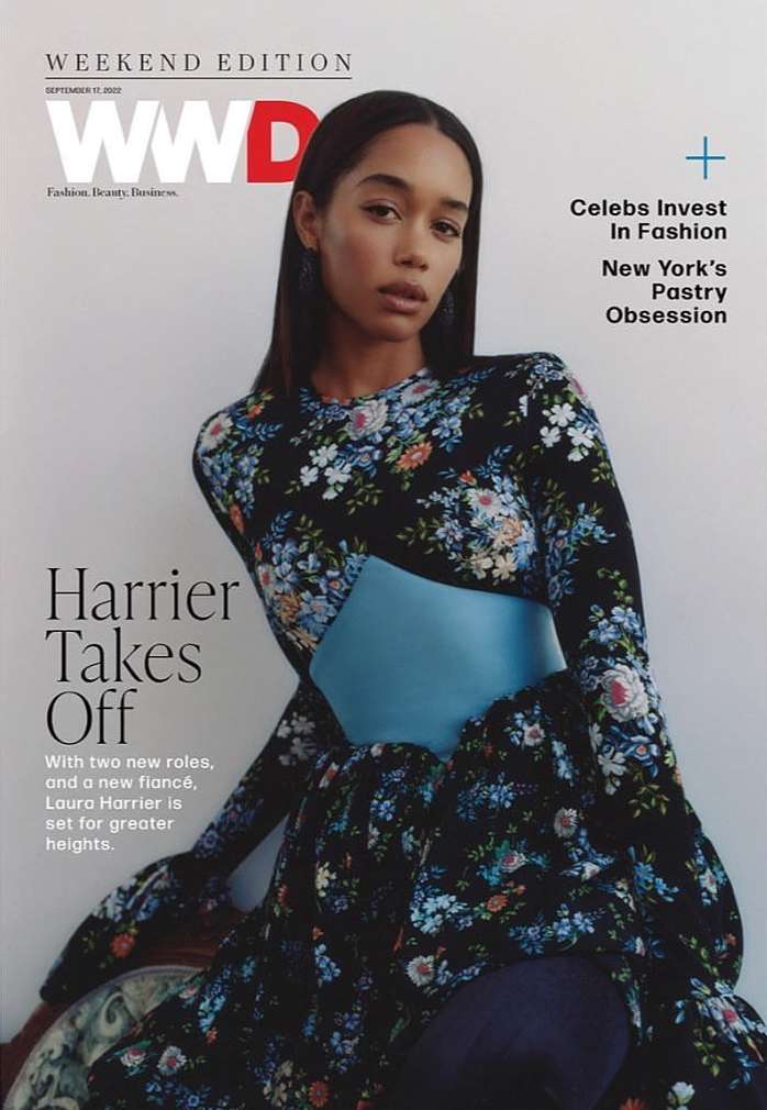 Laura Harrier wears a floral dress with a light blue belt on a WWD magazine cover. The masthead is red and white.