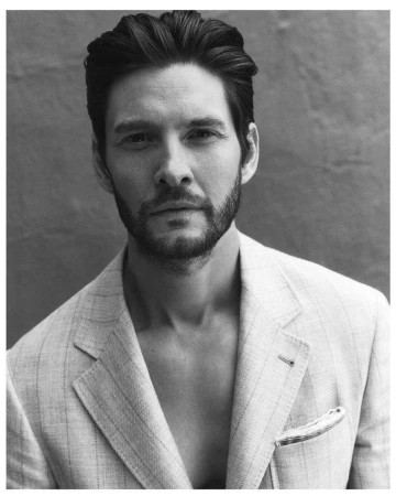 Portrait of Ben Barnes wearing a light patterned blazer against a dark textured background photographed by Jonny Marlow.