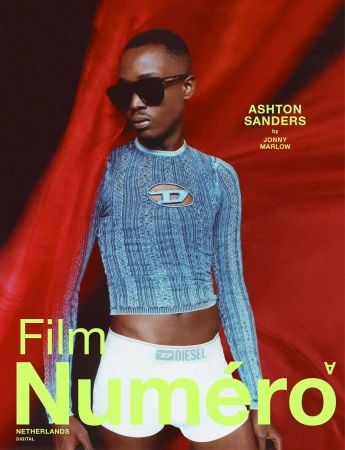 Ashton Sanders in oversized sunglasses and blue cutout top against flowing red fabric