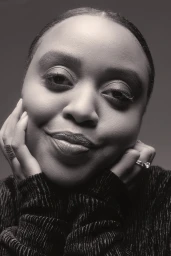 Close-up monochrome portrait of a black woman smiling with hands on cheeks