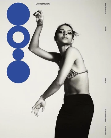 A monochrome fashion-style portrait features a woman in a bra top and skirt, with a geometric blue graphic to the side on an off-white background.