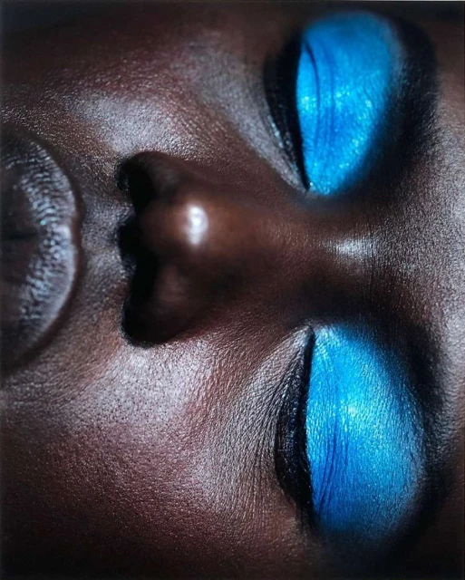 Close-up portrait of a Black woman with vibrant blue eyeshadow, showcasing the beauty look, skin texture, and makeup artistry.