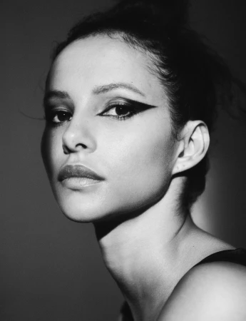 Close-up portrait of a woman with dramatic black winged eyeliner in monochrome lighting by Sharif Hamza.