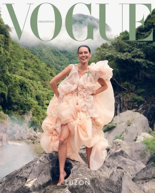 Vogue Philippines cover featuring a smiling adult female model in a voluminous peach dress, posing on rocks with a lush mountain background.