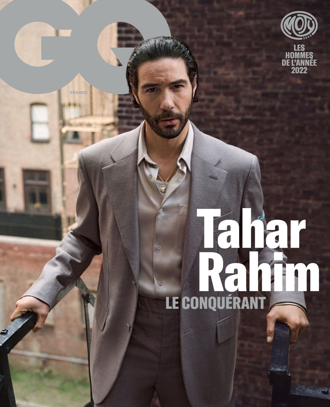 GQ magazine cover featuring Tahar Rahim in a suit on a balcony with a brick building backdrop, showcasing men's fashion and celebrity.