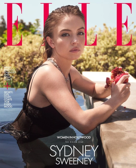 Sydney Sweeney on the cover of Elle Magazine, wearing a black bathing suit and silver necklace, holding a pomegranate with outdoor background.