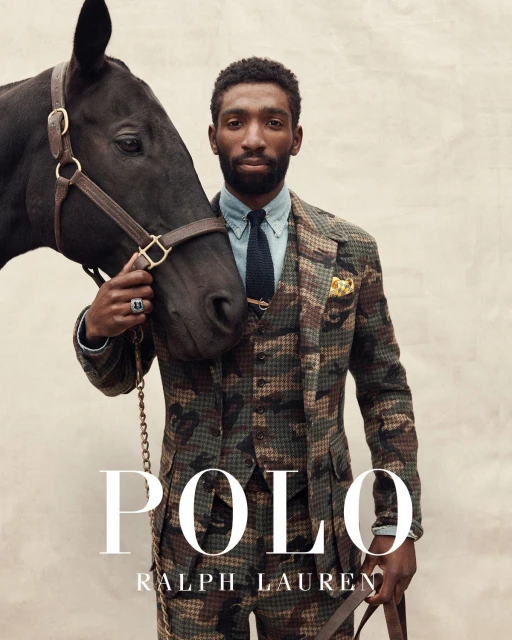 Black man in a camouflage suit stands with a black horse, both elegantly posed against a neutral backdrop for a Ralph Lauren ad.