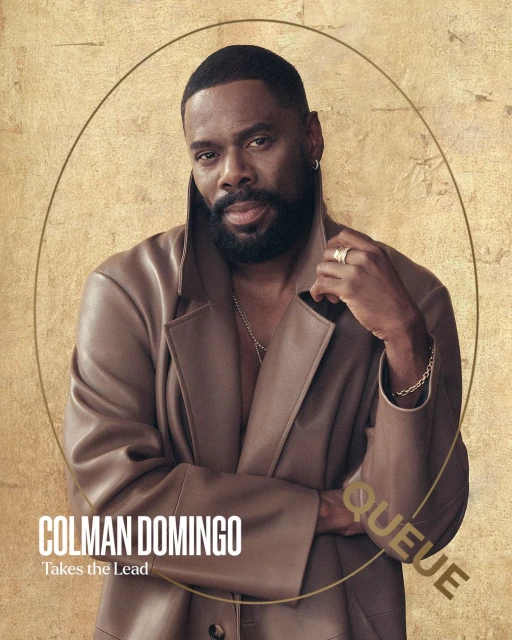 Headshot of Colman Domingo in a leather coat against a textured gold backdrop, framed by an oval, with his name and the word 'QUEUE' visible.