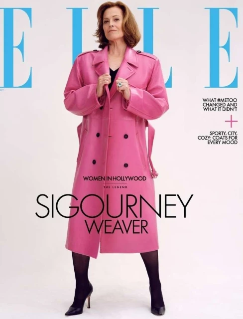 Magazine cover featuring Sigourney Weaver in a pink trench coat, black stockings, and heels, standing against a white backdrop. Elle logo.