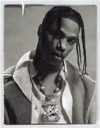 Portrait of Travis Scott with braided hair wearing a white shirt and statement pendant necklace by photographer Sharif Hamza