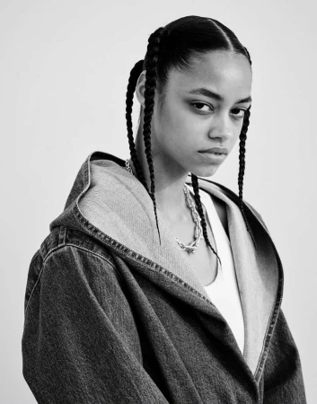 Monochrome portrait of a woman with braided hair wearing a denim hooded jacket photographed by Sharif Hamza.