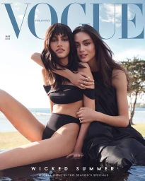 Two women wearing black swimwear posing by an outdoor pool in a fashion magazine cover photograph shot by Sharif Hamza