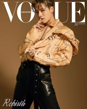 Man wearing a tan printed jacket and black leather trousers posing against a brown background for Vogue Singapore magazine