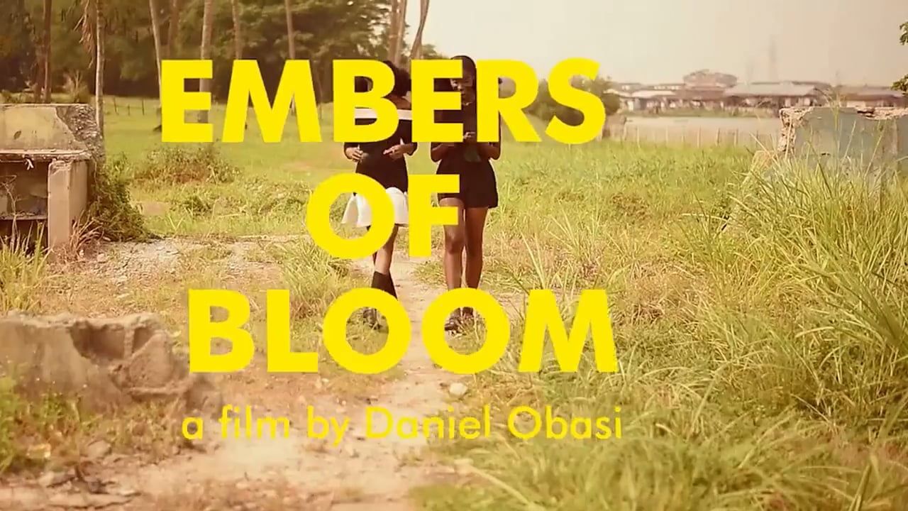 Two young women walk on a grassy path in a rural setting. Title text overlay: "Embers of Bloom," film by Daniel Obasi.