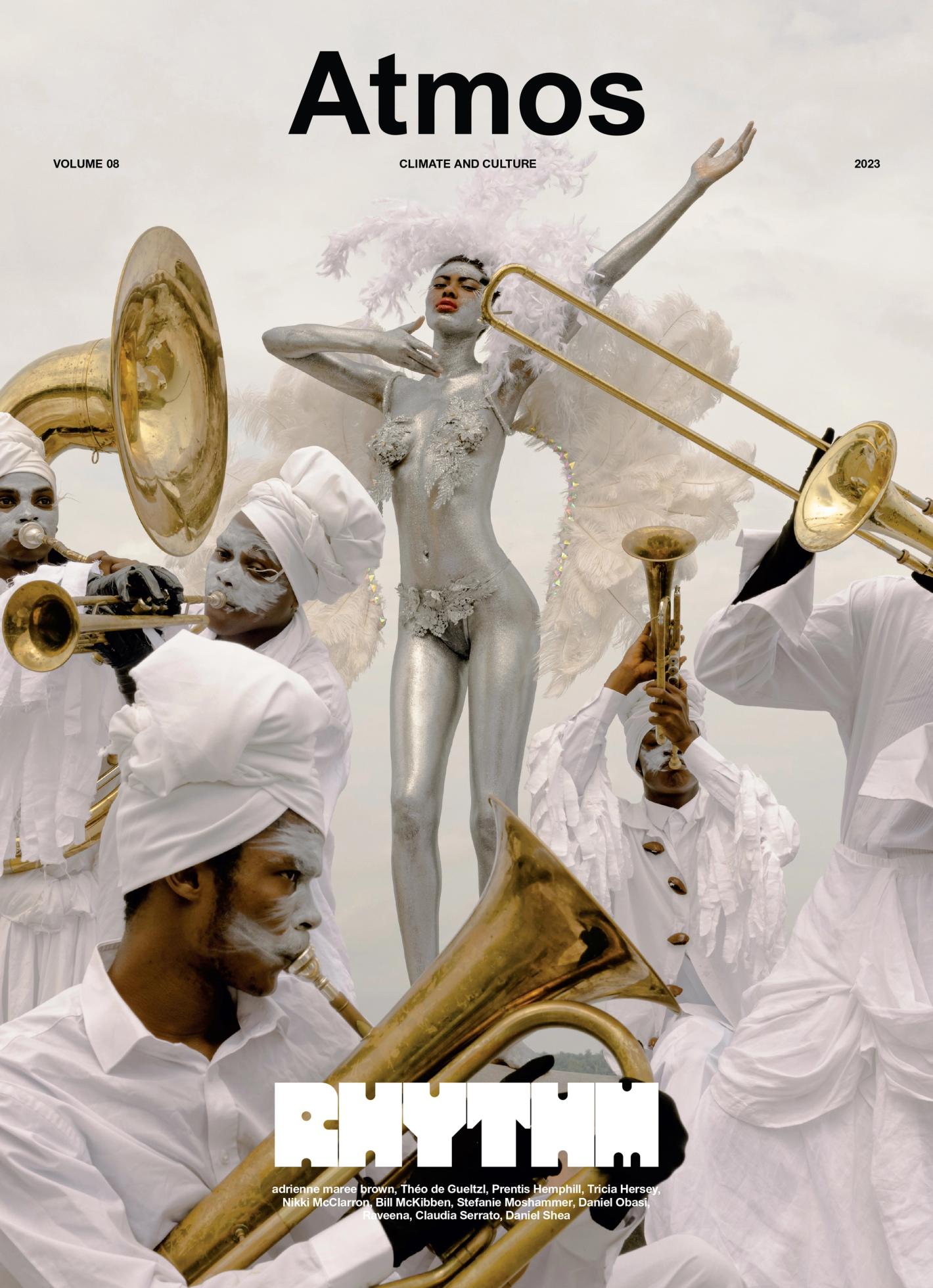 Magazine cover featuring a woman covered in metallic paint posing with musicians playing brass instruments in white outfits.
