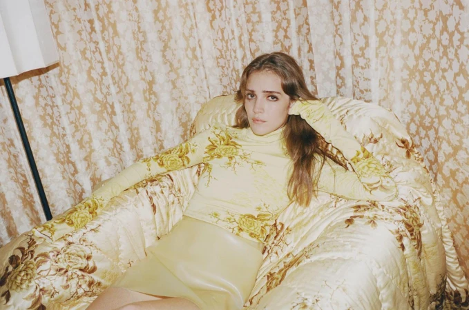 Woman in floral turtleneck and skirt seated on a matching floral patterned armchair in New York by Lorenz Schmidl.