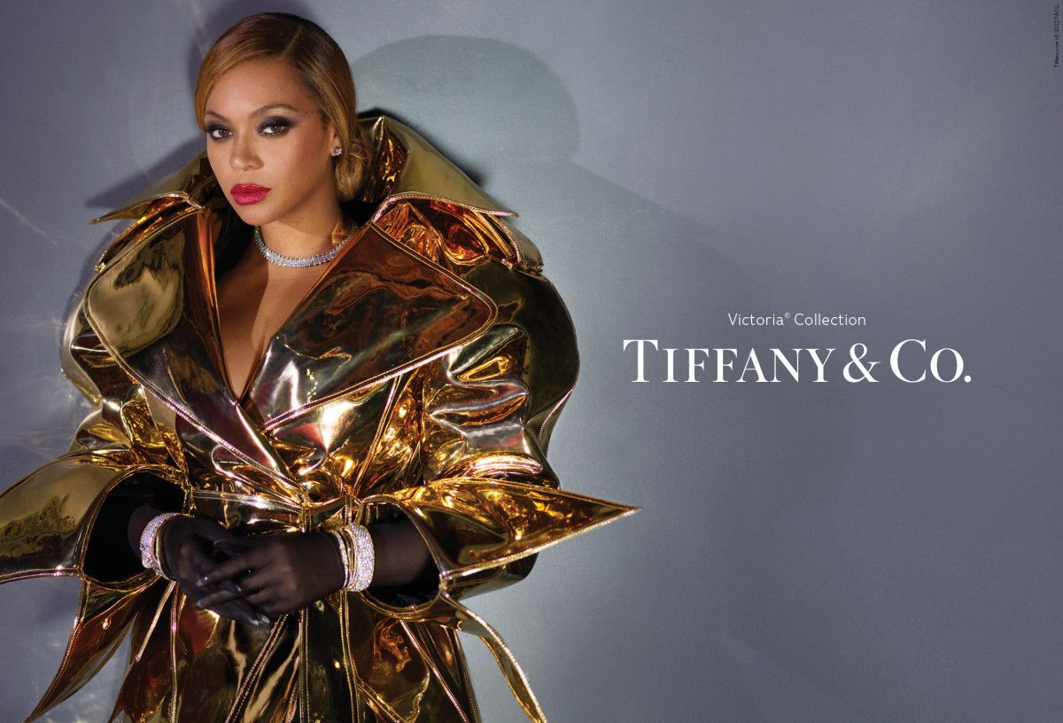 Adult female in a shiny gold coat and black gloves wearing diamond bracelets and necklace for Tiffany & Co. jewellery advertisement.