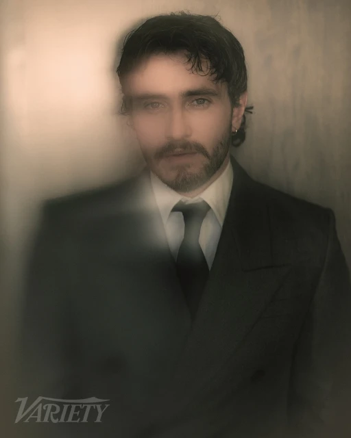 Portrait of a handsome adult male wearing a suit and tie in a studio setting with soft lighting and diffused focus.