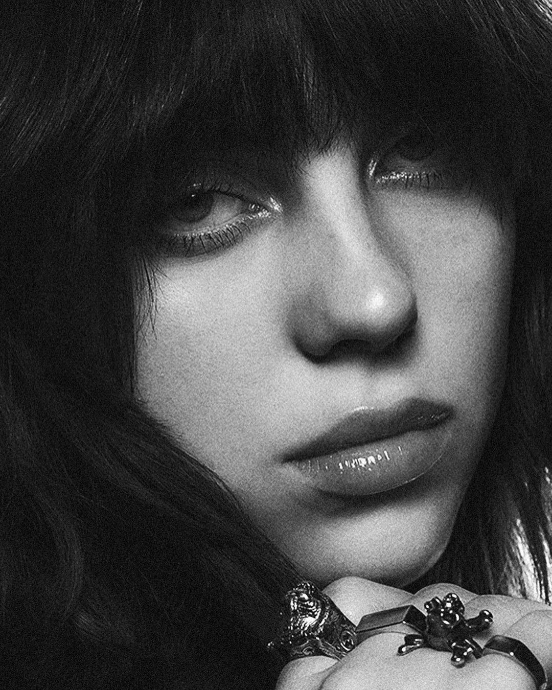 Striking black and white close-up portrait of a female with dark hair, featuring detailed rings and subtle studio lighting.