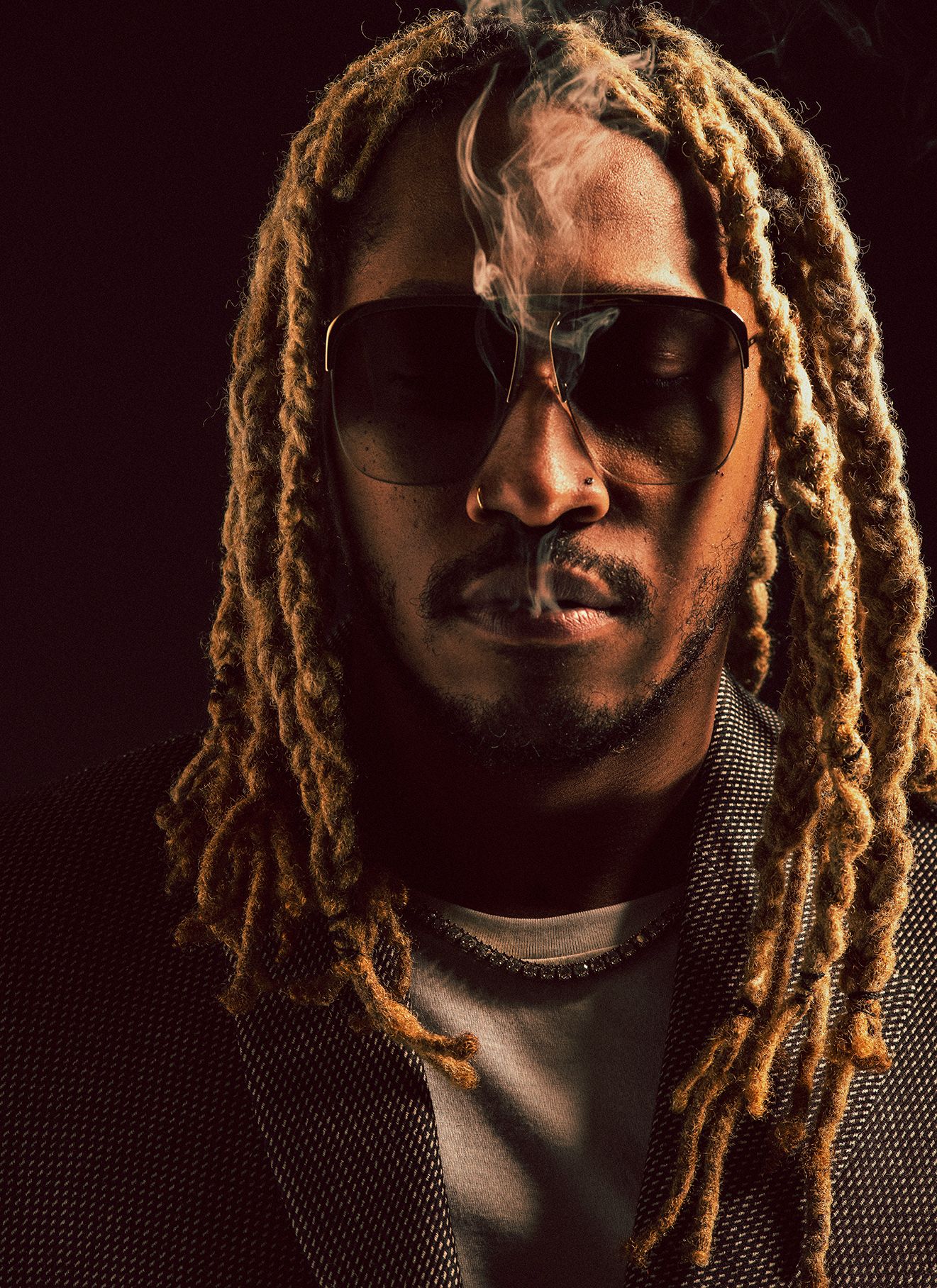 Portrait of Future, the American rapper, in a close-up shot, wearing sunglasses and a blazer, with smoke rising near his face.