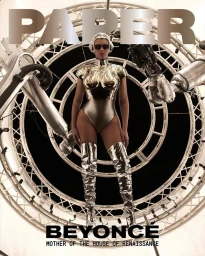 Beyonce wearing metallic robotic bodysuit and thigh-high boots standing before a circular mechanical structure