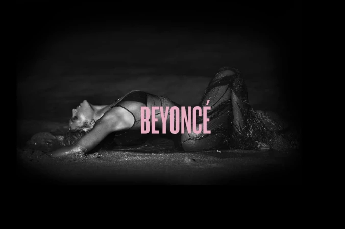 Monochrome portrait of Beyonce lying on a sandy beach at night wearing a dark sheer sparkling gown, photographed by Mason Poole.