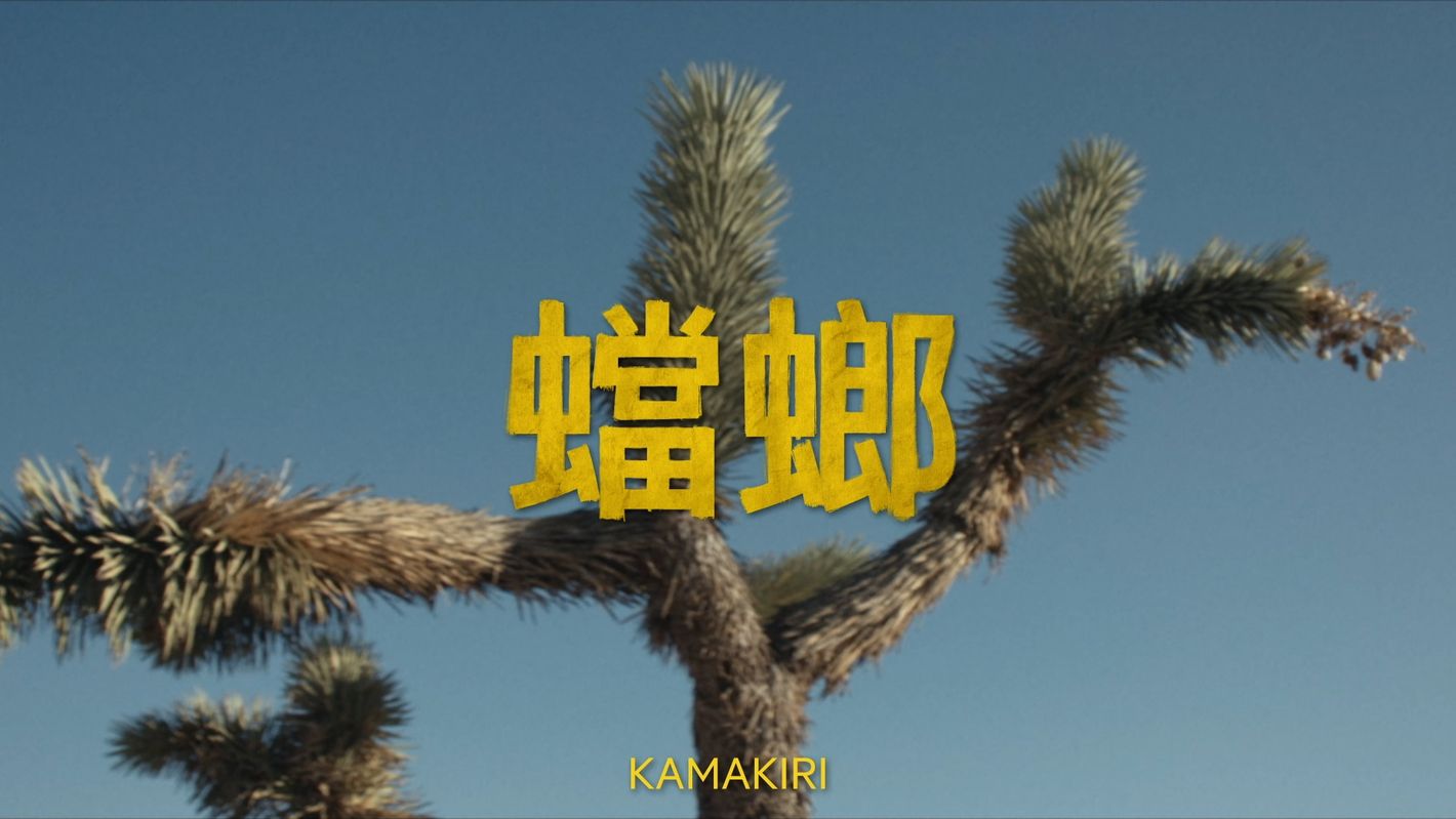 Scenic desert landscape featuring a Joshua tree silhouetted against a clear blue sky, overlaid with Japanese text, creating a striking contrast.