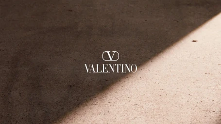 Valentino logo displayed on a textured stone surface with a sharp diagonal shadow dividing light and dark areas.