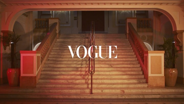 Elegant architectural stairs and planters, featuring the word 'VOGUE' prominently displayed in the center, under warm lighting.