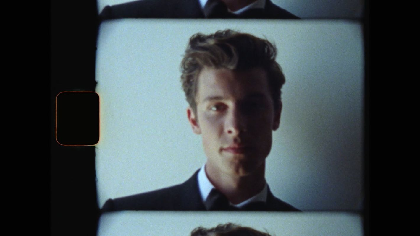 Close-up headshot of a young adult male wearing a black suit and bow tie, captured on film with a film border visible in the frame.