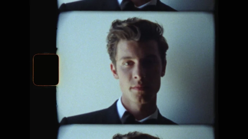 Film strip frame showing a man wearing a black suit and bow tie against a light background, directed by Max Bartick.