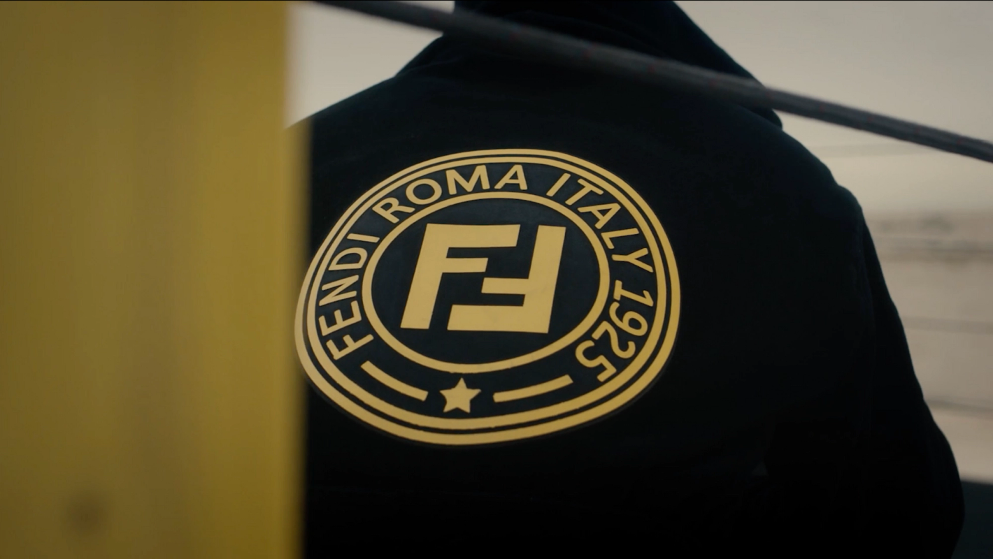Close-up of a black jacket with a prominent gold Fendi Roma Italy logo, showcasing the brand's emblem and established year.