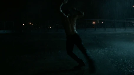 Shirtless man dancing in the rain on a rooftop at night captured by Kevin Frilet in Paris.