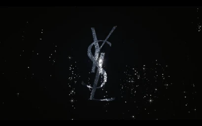 Sparkling silver YSL monogram logo centered against a black starry night background with glittering lights
