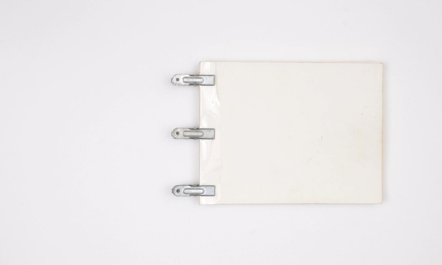 White square cardstock held by metal clip fasteners, centered on a solid white surface in a minimalist, eye-level studio shot.
