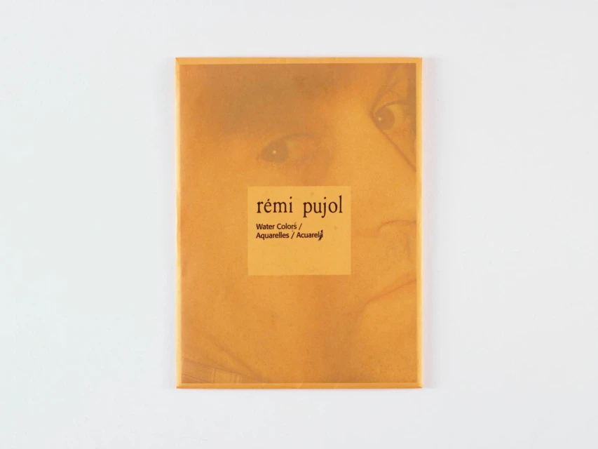 Art book cover featuring the words 'rémi pujol,' 'Water Colors,' and 'Aquarelles,' with a faded image of a face on a yellow background.