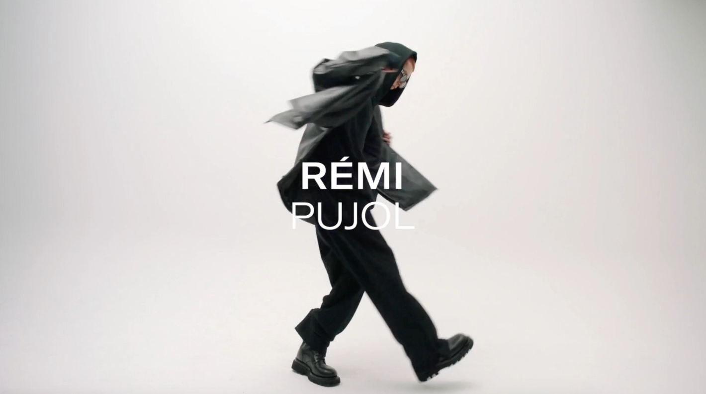 Person in black clothing walking in a studio setting, motion blur on pants and blazer. Text overlay reads 'Remi Pujol'.