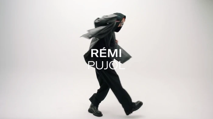 Person in a dark hooded jacket and trousers captured mid-motion against a plain white background.