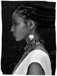 Black-and-white profile portrait of a woman with braided hair wearing a statement chain necklace and shell earring by Remi Pujol