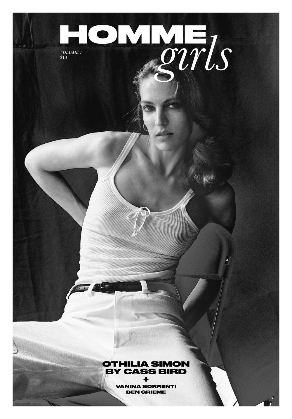 Black and white fashion portrait of a young adult woman in a white tank top and jeans, sitting in a studio with soft lighting.