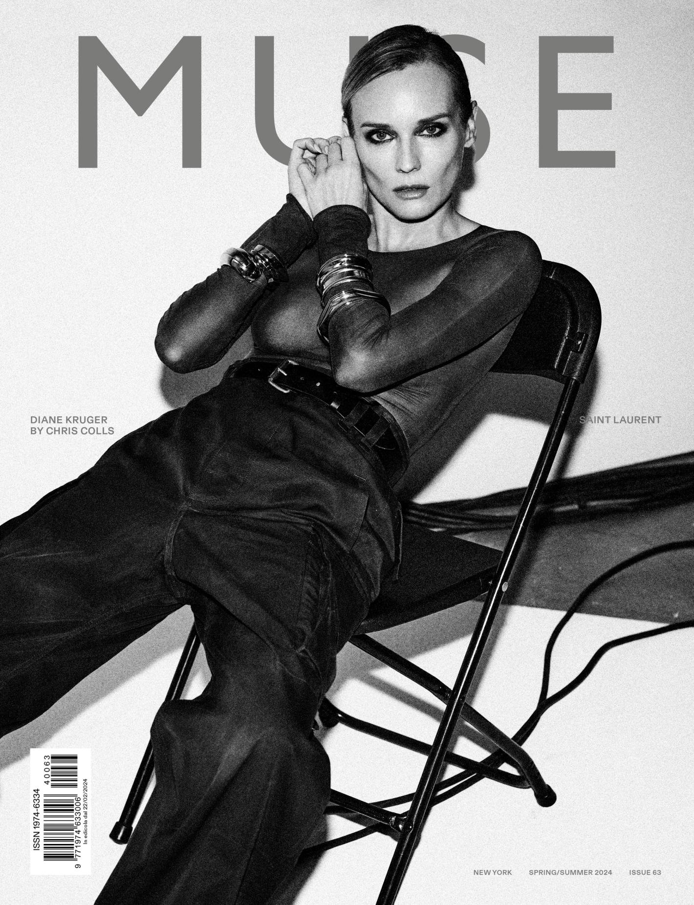 Diane Kruger poses on a black chair in front of a stark white background, wearing a long-sleeved top, wide leg pants, and metallic bracelets.