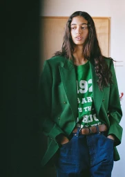 Model with long dark hair wearing a green blazer over a green t-shirt and blue jeans, styled by Elissa Santisi.